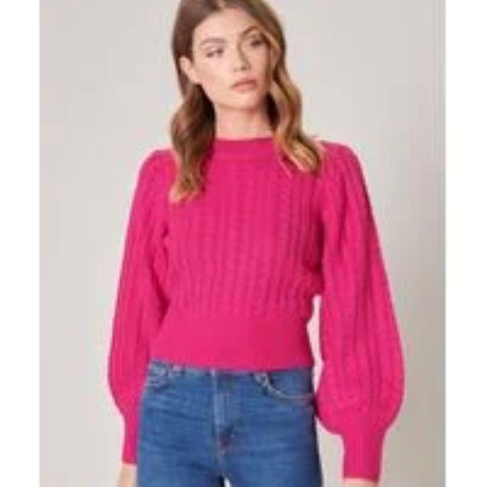 Pink cable knit sweater, slight poof in shoulder.